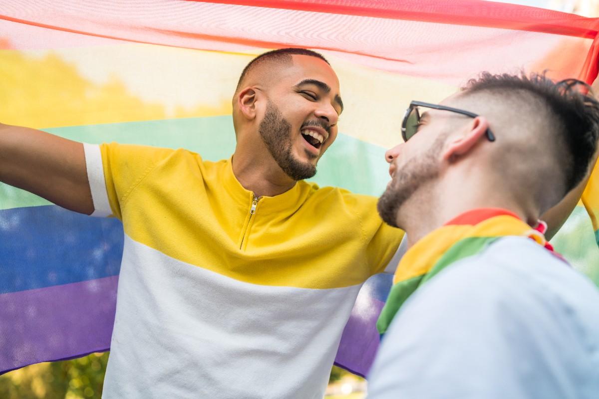 gay couple embracing showing their love with rainbow flag 1