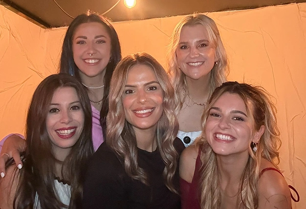 Close-up of five smiling female friends having a great time and posing together at a singles event or night out.