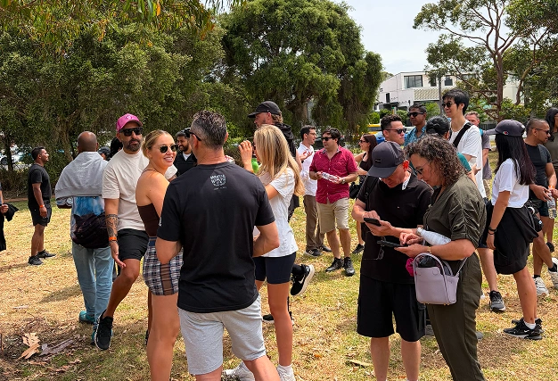 Diverse group of singles mixing and socializing outdoors in a sunny park setting during a casual singles event.