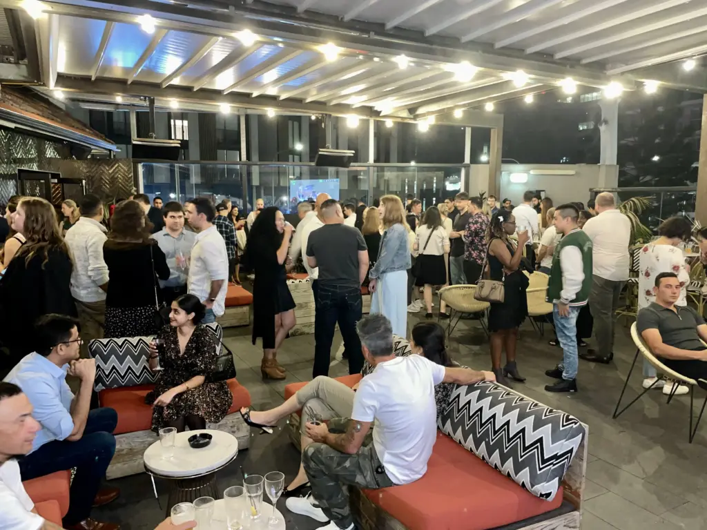Crowded rooftop lounge networking event.